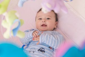 Happy baby lying in his crib smiling