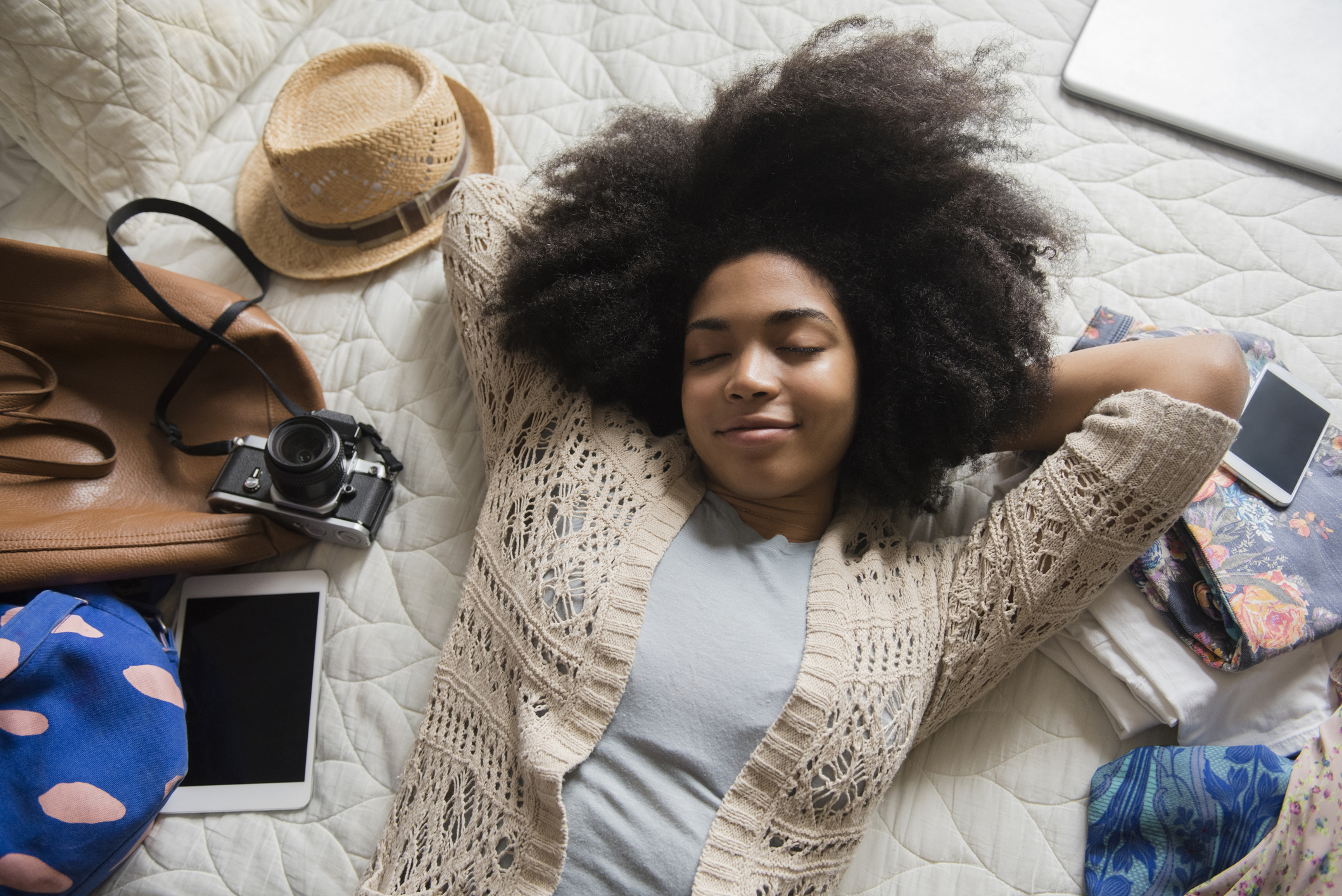 African American woman laying on bed anticipating travel