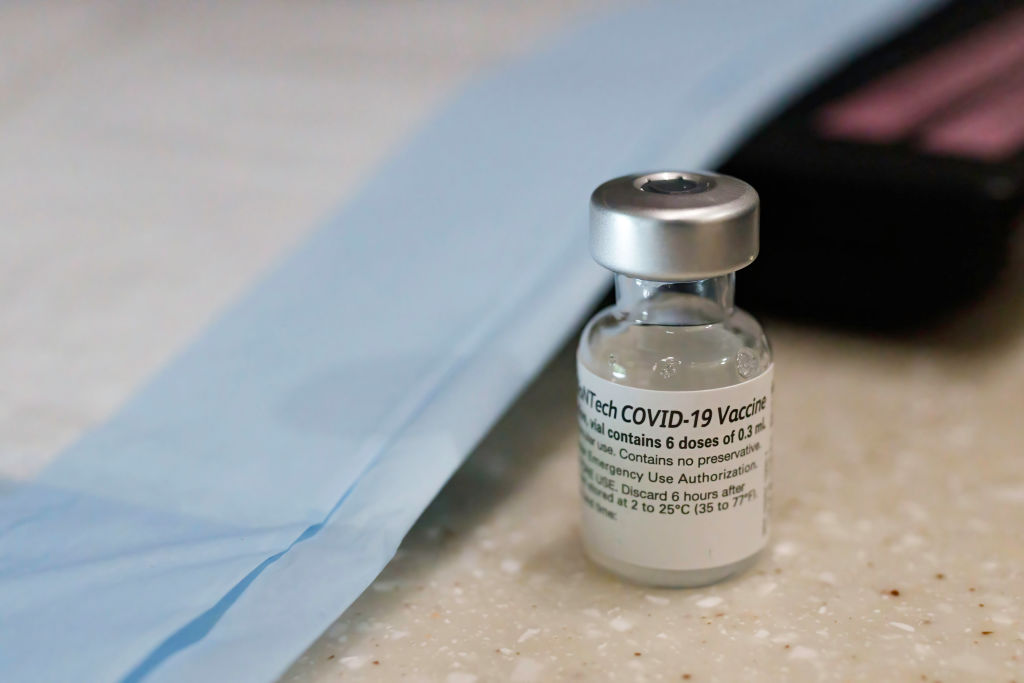 A vaccine vial sits next to PPE, ready to be loaded into a...