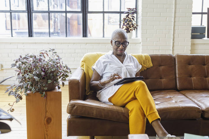 Senior businesswoman working on tablet computer from sofa at home