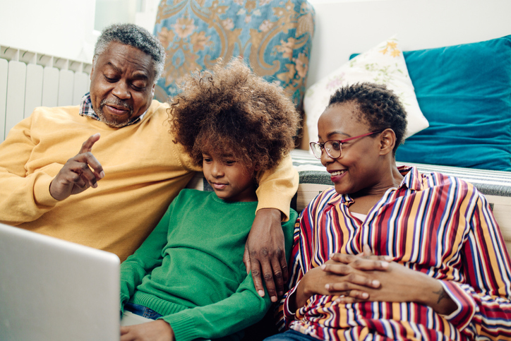 Happy African-American girl and her grandparents making a video call on a laptop