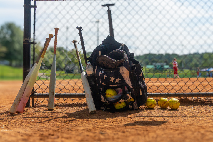 Girls' Softball Team Equipment and Players in the Background