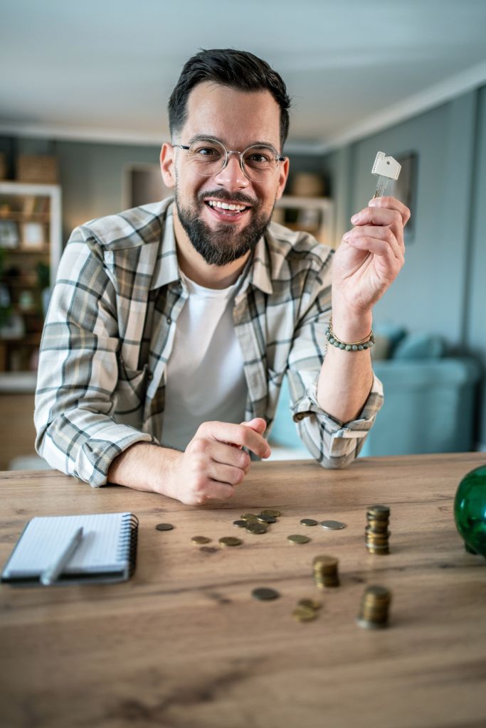 Happy man holding new house key after counting savings