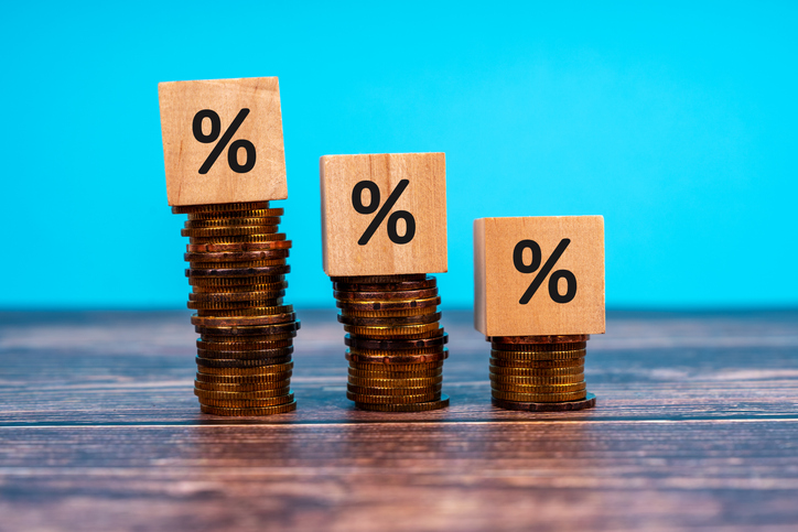 Stacks of coins with wooden block place on each stack and percentage symbol written on them. Blue background
