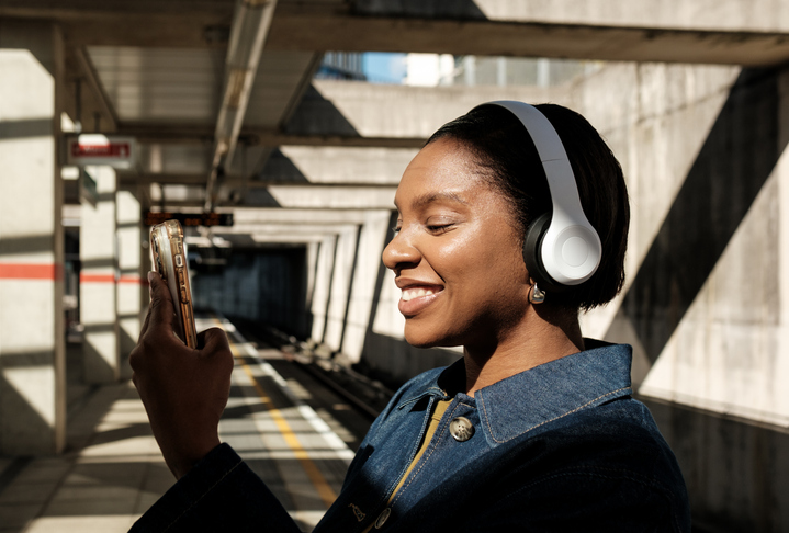 Young black woman listening to music on her phone at subway station